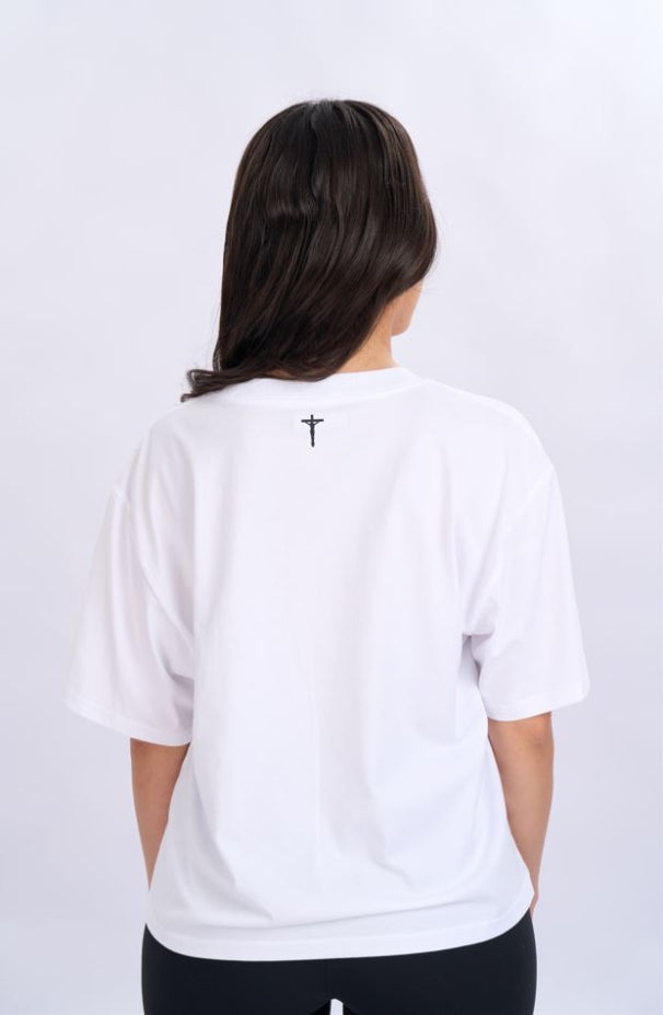 Person wearing a white t-shirt with a cross design on the back against a light grey background