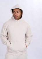 Person wearing a beige hoodie on a white background
