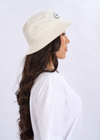 Woman wearing a beige bucket hat and white t-shirt on a light grey background