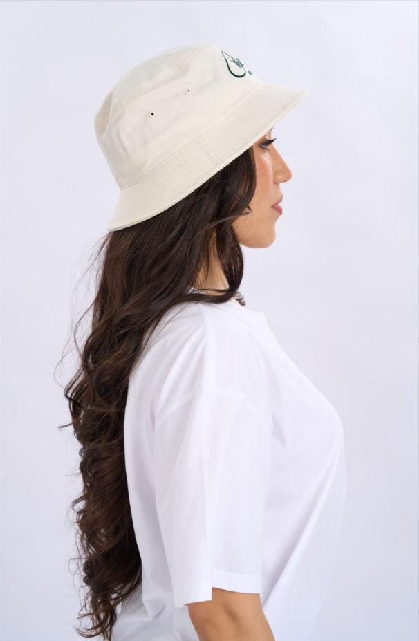Woman wearing a beige bucket hat and white t-shirt on a light grey background