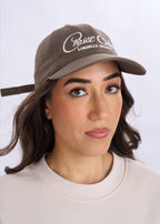 Woman wearing a brown cap with white text on a plain background