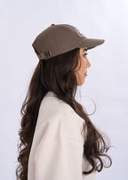 Woman wearing a brown cap and beige coat against a white background