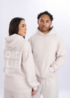 Two people wearing matching beige hoodies with text on a white background