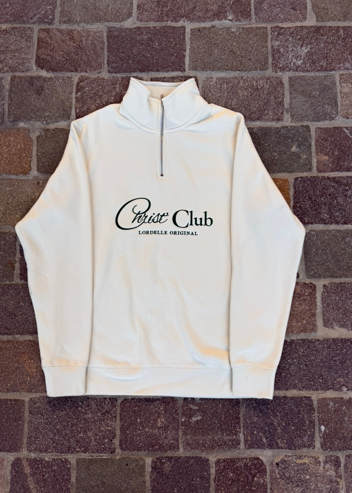 White hoodie with 'Crest Club' logo on a brick background
