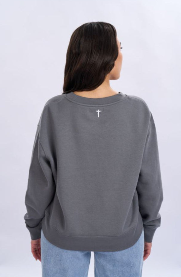 Person wearing a grey sweatshirt with a cross on the back against a white background