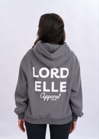 Person wearing a grey hoodie with 'LORD ELLE Apparel' text on the back against a white background