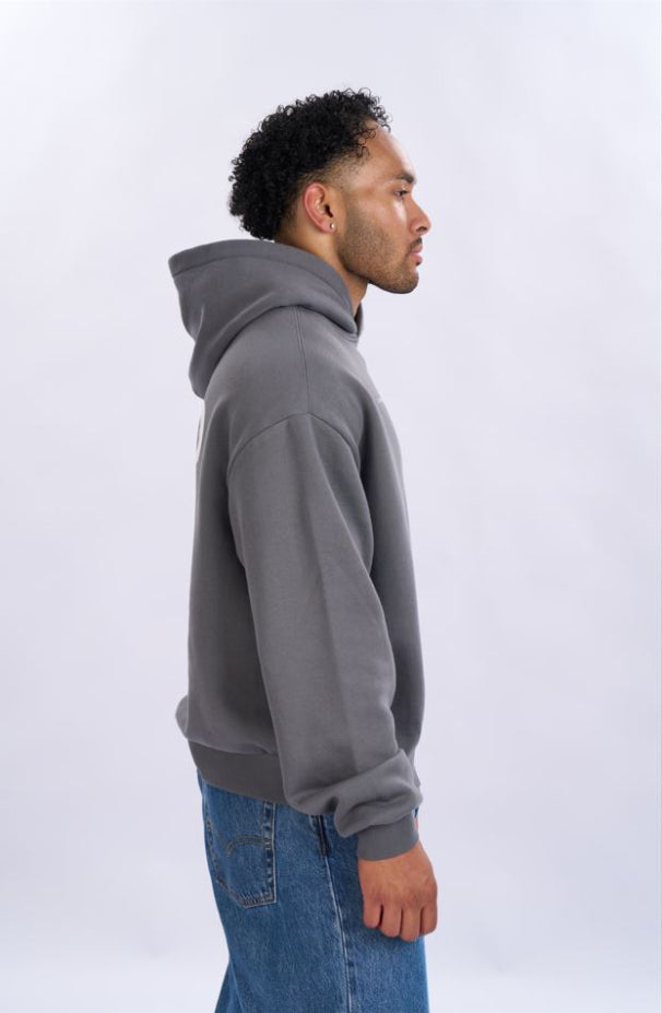 Man wearing a grey hoodie and blue jeans on a white background