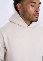 Man wearing a beige hoodie with 'Supreme' logo on a white background